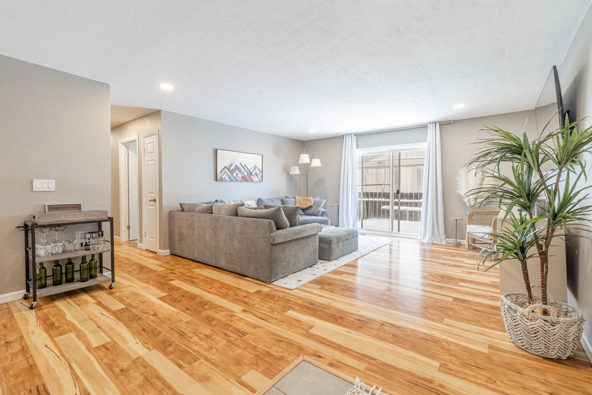 The same Columbus Way living room repainted in warm greige with a full sectional floated on a large rug and layered white drapery