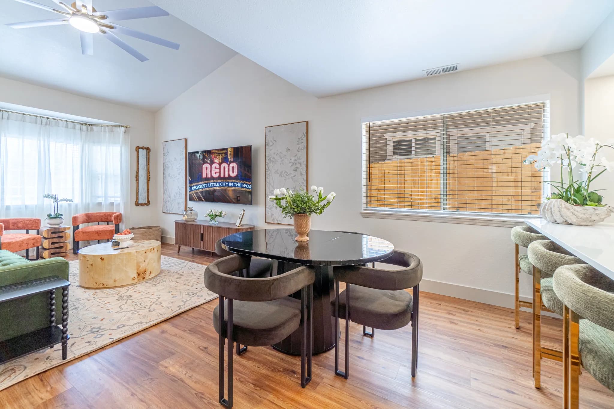 The same Tarn Street living room furnished into dining, seating, and counter zones with a green sofa and terracotta chairs