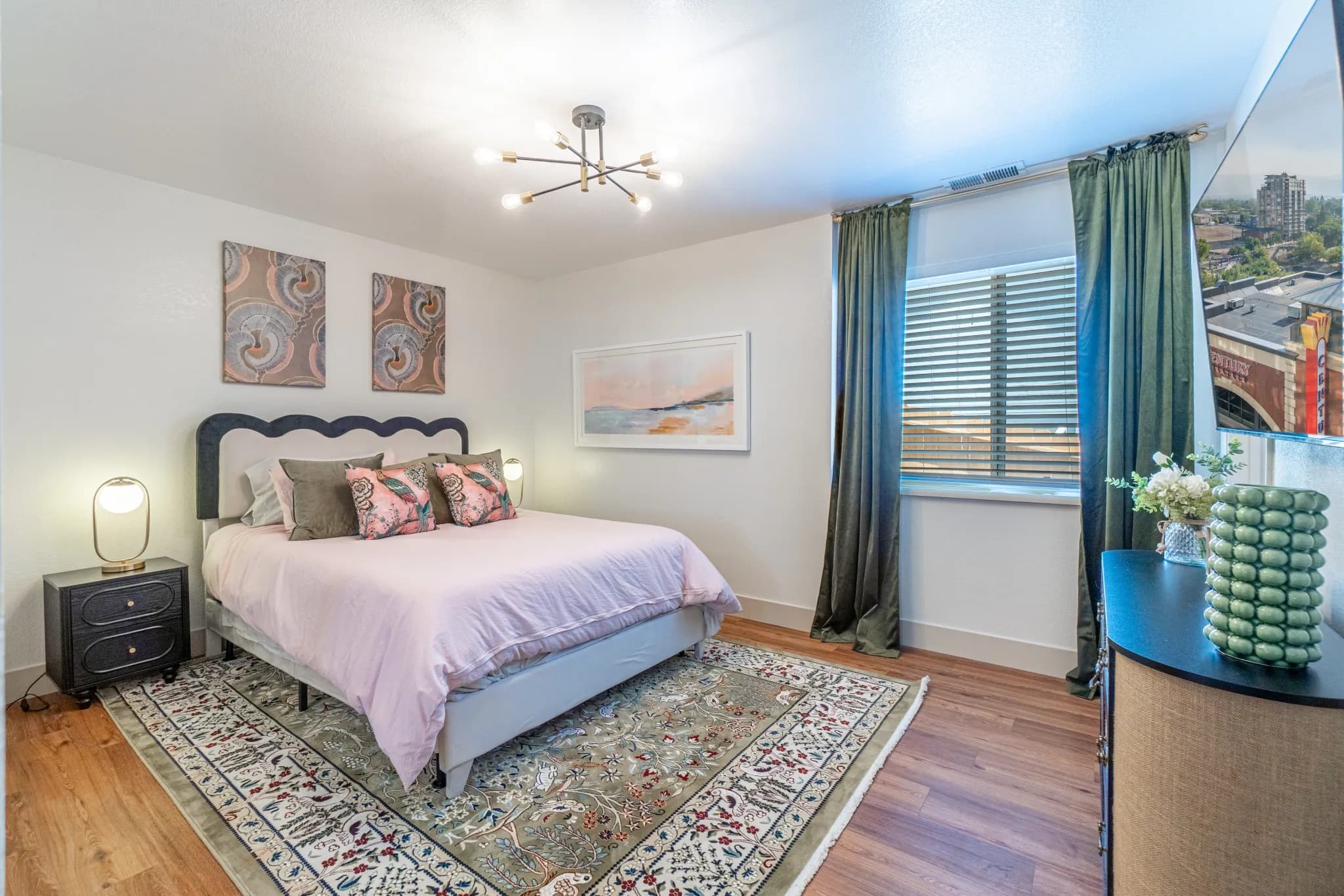 The same Tarn Street primary bedroom with an upholstered queen bed, layered pillows, and full-height green velvet blackout drapes